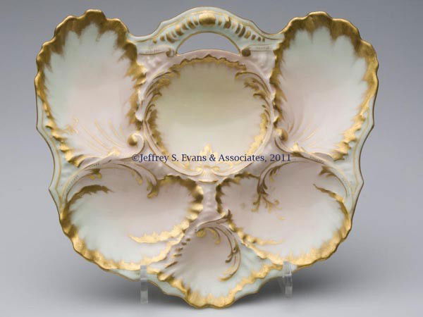LIMOGES PORCELAIN OYSTER PLATE: LIMOGES PORCELAIN OYSTER PLATE, pastel polychrome and gilt decoration, semicircular form with open handle, marked underglaze, including "Patent Applied For". Martial Redon & Co., Limoges, France. Four