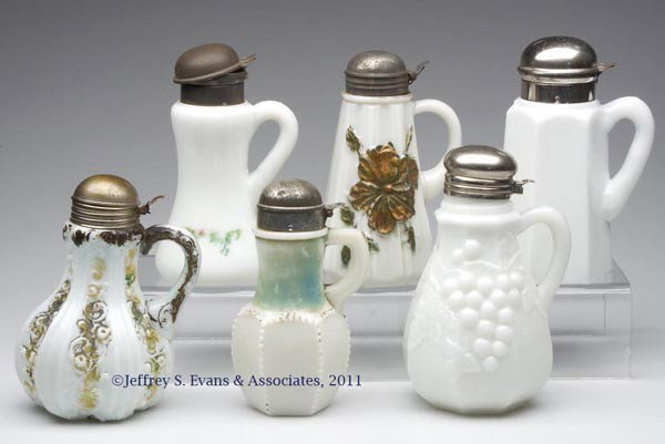 VARIOUS PRESSED SYRUP PITCHERS, LOT OF SIX: VARIOUS PRESSED SYRUP PITCHERS, LOT OF SIX, opaque white/milk glass, four with decorations, including Giant Dogwood, and Paneled Scroll, period and mismatched lids. Fourth quarter 19th century. 6 1/4"