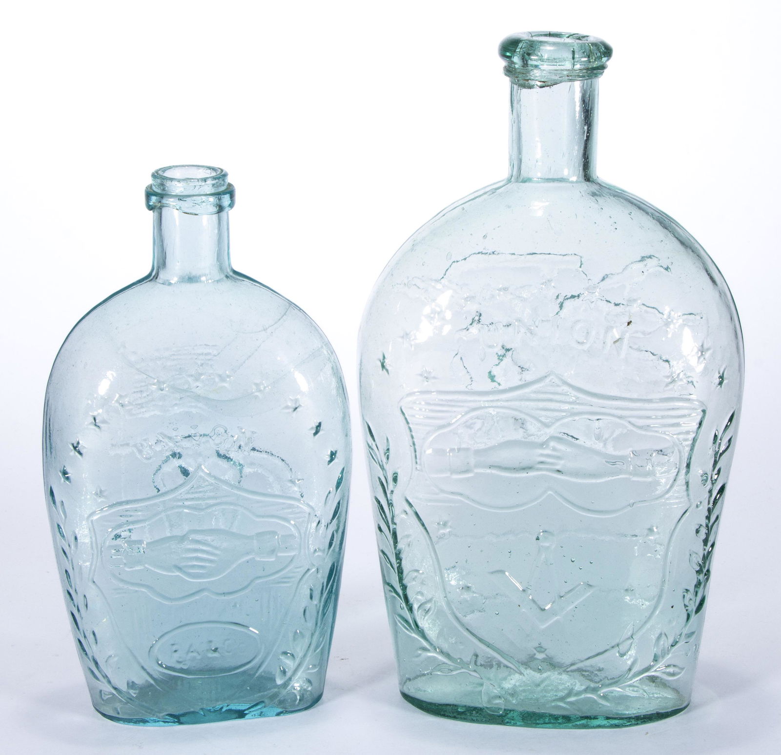 ASSORTED CLASPED HANDS HISTORICAL FLASKS, LOT OF TWO,: aquamarine, comprising a quart GIV-38 and a pint GXII-40, each having an applied lip, each having a plain base. Midwestern. 1860-1880. 7 1/2" to 9 1/4" H.Provenance: From the Eddie Tatum estate collec