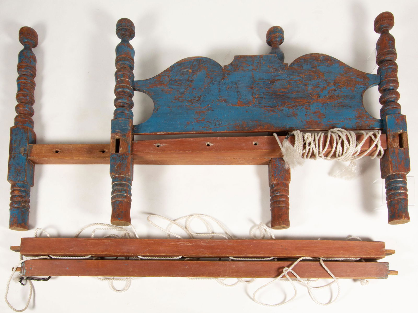 AMERICAN PAINTED PINE ROPE BED,: cut-out head and foot boards supported on well-turned posts and tall, turned legs, with side rails. Retains an old blue-painted surface. Probably Pennsylvania. First half 19th century. 42 1/2" H. Prov