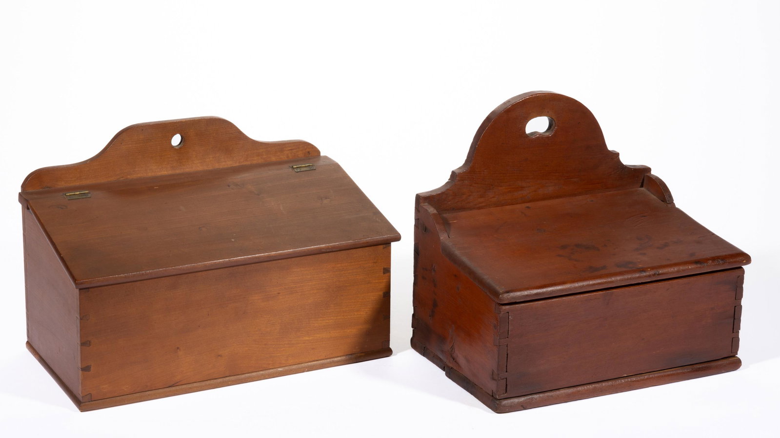 AMERICAN COUNTRY CHERRY AND PINE WALL BOXES, LOT OF TWO,: each with shaped backs, dovetailed construction, and hinged lids concealing an open interior. Poplar secondary wood. Each retaining an old surface with warm color. 19th century. 9 3/4" and 11" HOA. Pr