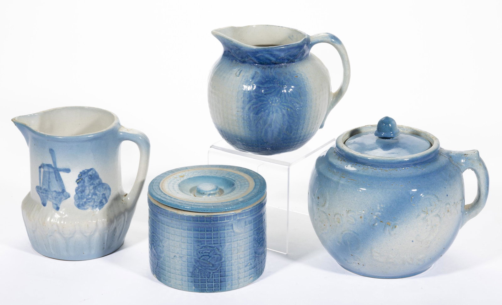 AMERICAN BLUE AND WHITE SPONGEWARE STONEWARE ARTICLES, LOT OF FOUR,: comprising a Windmill and Bush pitcher, a bulbous-form pitcher with Poinsettia design on a square woven cane background, a Boston Baked Beans crock having cover with acorn finial, and a low, cylindric
