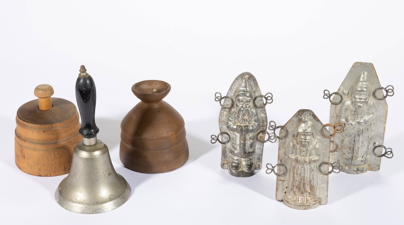ASSORTED DOMESTIC ARTICLES, LOT OF FIVE,: comprising a treen sheaf-of-wheat butter mold, a white brass hand school bell, and three tin Santa Claus chocolate molds. Together with a pottery vase bearing an unidentified stamped signature. Six pi
