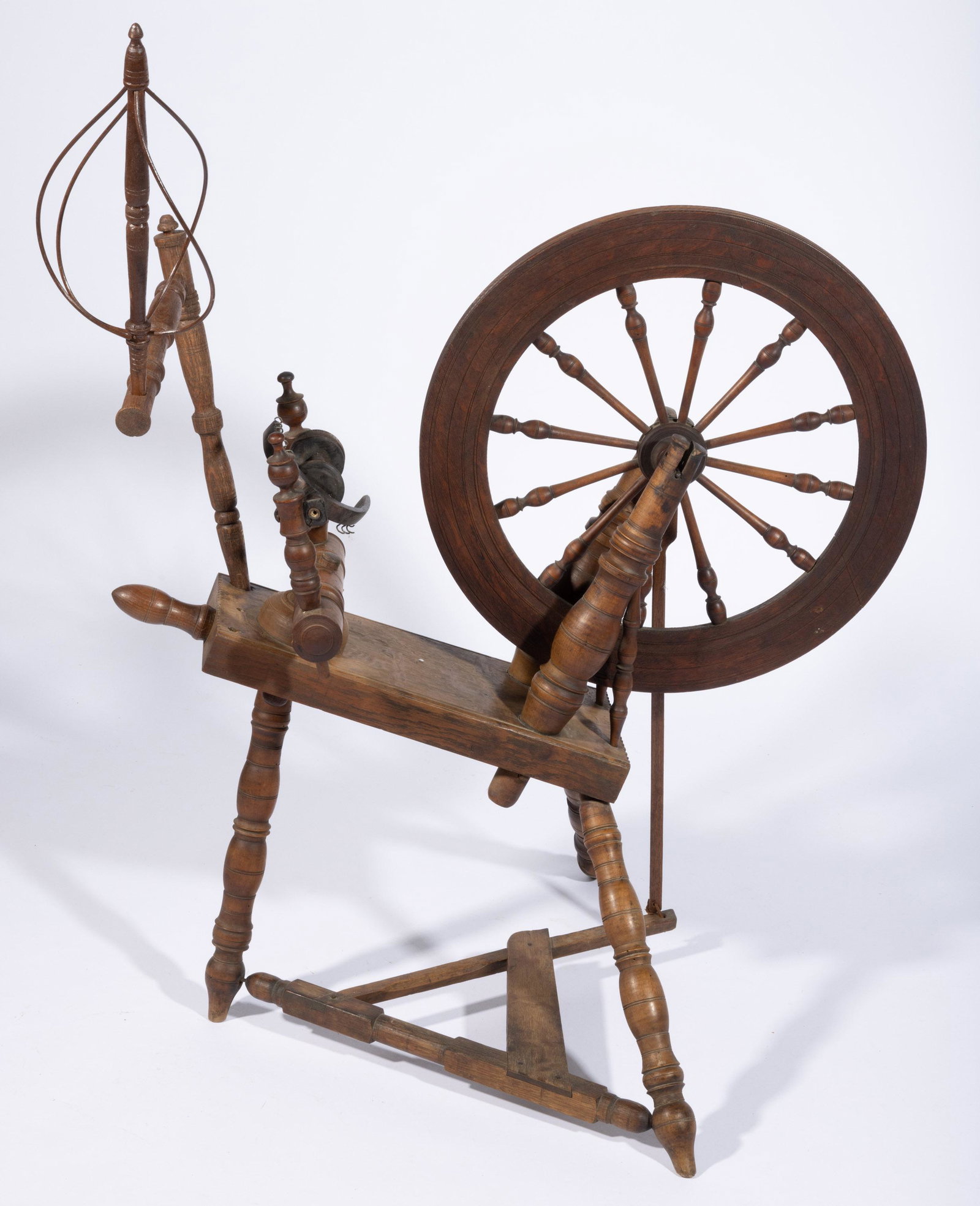 VALLEY OF VIRGINIA FLAX SPINNING WHEEL,: oak and maple, baluster-turned spindles, supports, and splayed legs, chip-carved and molded-edge bed, with bobbin, distaff and support likely replaced. Retains an old, dry surface. First half 19th cen