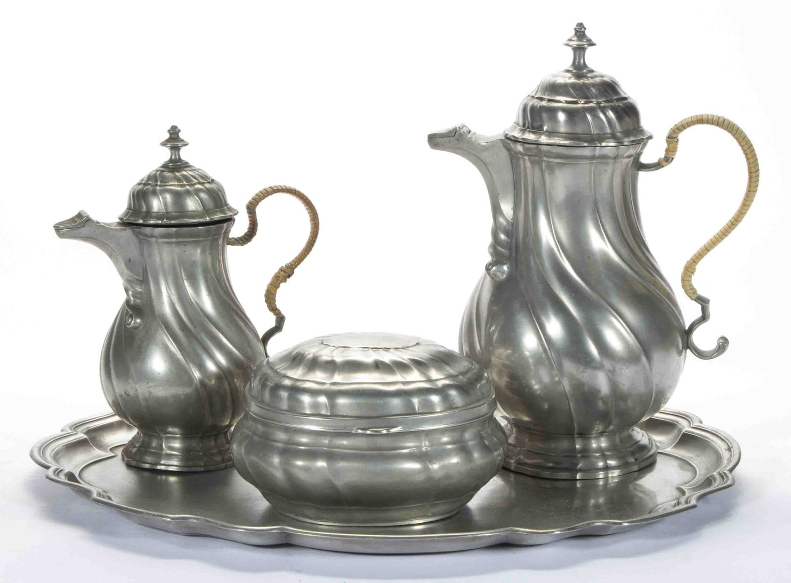 ASSEMBLED REVIVALIST PEWTER FOUR-PIECE COFFEE SET,: comprising a matching paneled swirl pattern coffee pot and creamer each with a wicker covered handle, and a sugar bowl, each with a hinged cover, each with angel mark between "A" and "W"; fitted on a