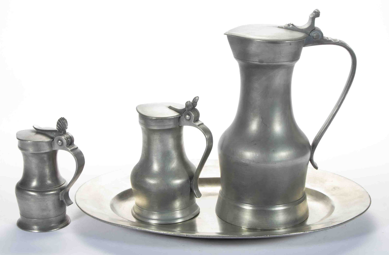 ASSORTED REVIVALIST PEWTER TABLE ARTICLES, LOT OF FOUR,: comprising three French-style pitchers, including the large example of Parisian-style, marked for Nicholas Deschamps of Liege, the mid-size example with double-acorn thumbrest and an undetermined mark
