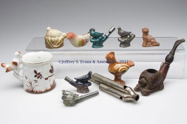 TEN ASSORTED FIGURAL WHISTLES: TEN ASSORTED FIGURAL WHISTLES, metal and ceramic, mug with whistle handle. Along with a carved wood turtle figural pipe. Eleven (11) pieces total. 19th and 20th century. 1 1/2" to 3 1/2" H. Provenance