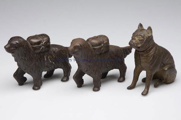THREE ANIMAL-FORM CAST-IRON STILL BANKS: THREE ANIMAL-FORM CAST-IRON STILL BANKS, comprising a Boxer (Bulldog) and two small St. Bernards with Pack, each with original surface. First half 20th century. 3 3/4" and 4 1/4" H. Provenance: From