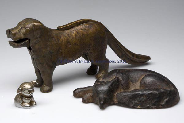 THREE CAST METAL ANIMAL FIGURES: THREE CAST METAL ANIMAL FIGURES, comprising an iron sleeping fox doorstop, a bronze/bell brass dog nutcracker and an iron "BUCKI / CARBONS / RIBBONS" paperweight. First half 20th century. 1 1/2" to 4 