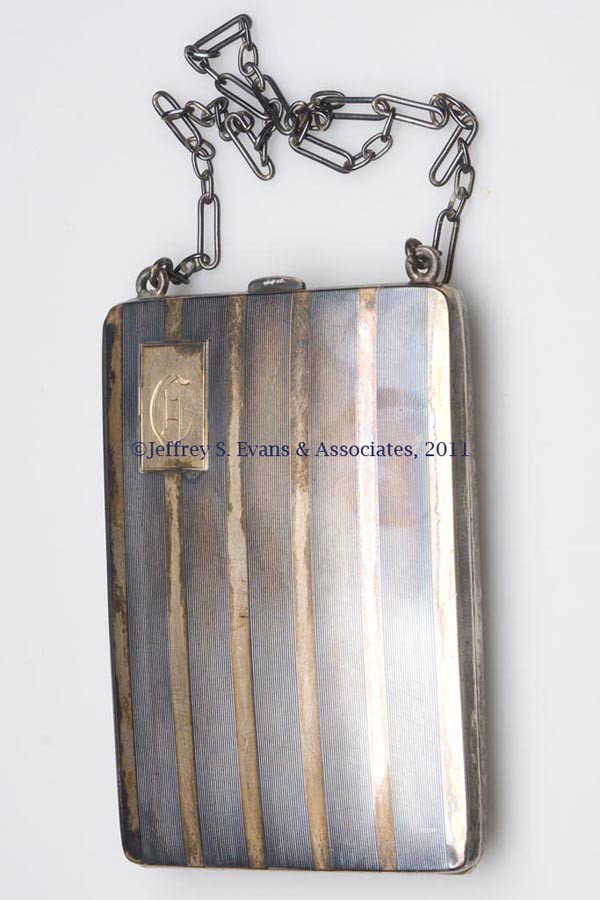 STERLING SILVER AND 14K GOLD CHANGE PURSE: STERLING SILVER AND 14K GOLD CHANGE PURSE, gold inlays on cover, fitted with two change holders, mirror and card clip, original chain, marked for James E. Blake Co. Total weight: 3.5 ozt First half 20