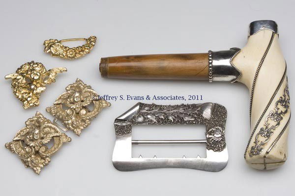 ASSORTED STERLING SILVER ACCOUTREMENTS: ASSORTED STERLING SILVER ACCOUTREMENTS, comprising a sterling mounted bone cane/umbrella handle, a one-piece buckle with applied crab and other marine ornaments, and two gold-washed two-piece buckles,