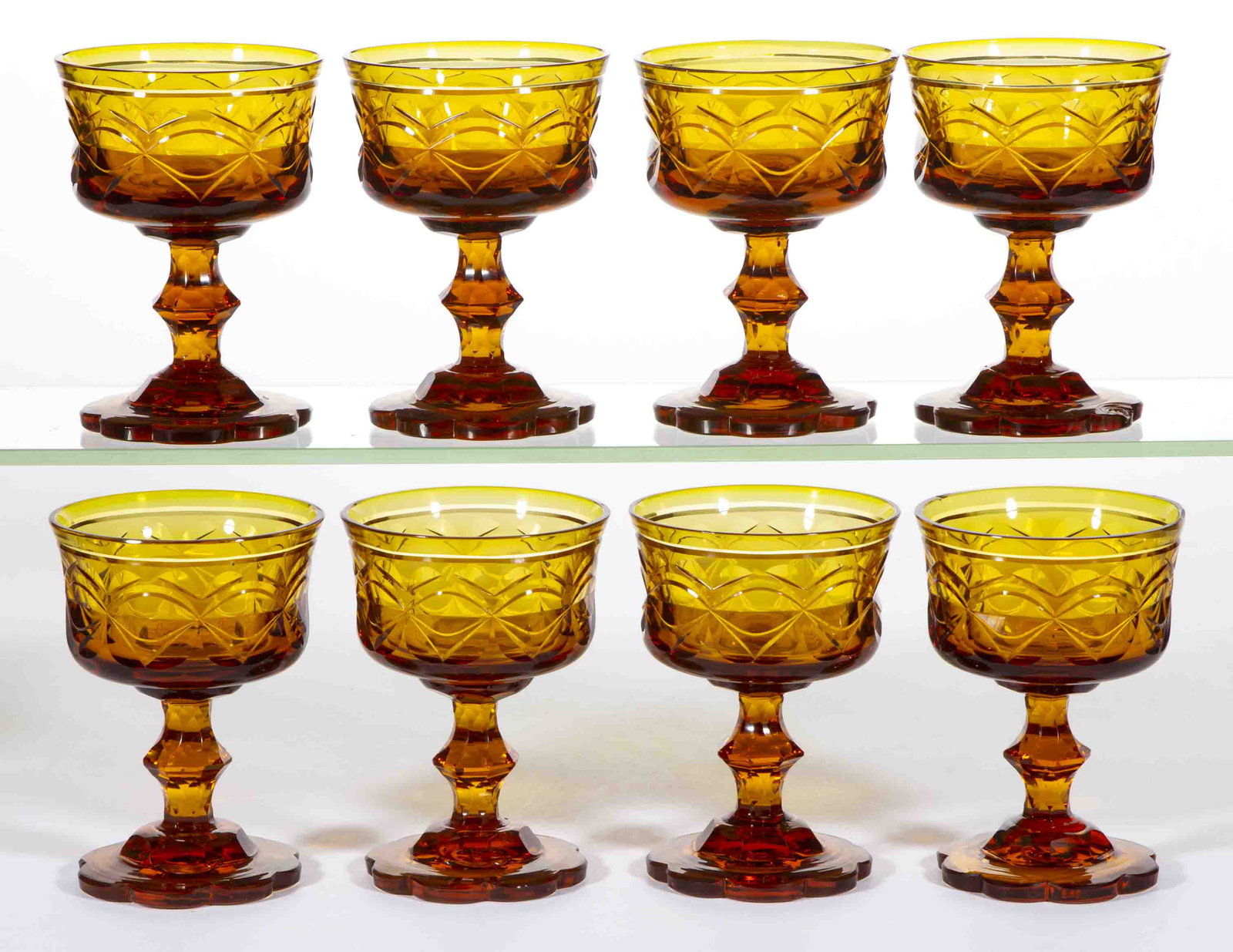 VICTORIAN AMBER CUT GLASS CHAMPAGNES, LOT OF EIGHT: VICTORIAN AMBER CUT GLASS CHAMPAGNES, LOT OF EIGHT, red amber, each having a shallow bowl with each having matching bisected ovals motif with lower chevrons, cut-faceted stems and scalloped feet. Make