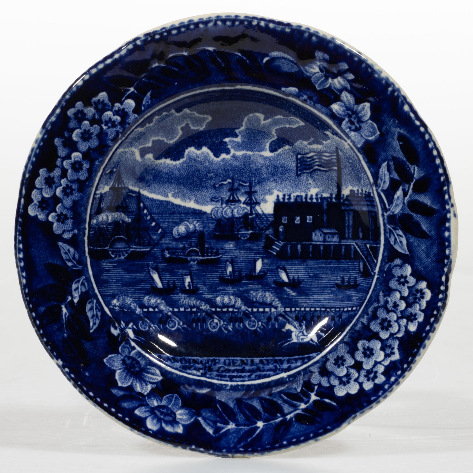STAFFORDSHIRE AMERICAN HISTORICAL TRANSFER-PRINTED CERAMIC CUP PLATE: STAFFORDSHIRE AMERICAN HISTORICAL TRANSFER-PRINTED CERAMIC CUP PLATE, featuring the "LANDING OF GEN. LA FAYETTE / at Castle Garden / 16 August 1824", printed below scene, depicting the arrival of the 