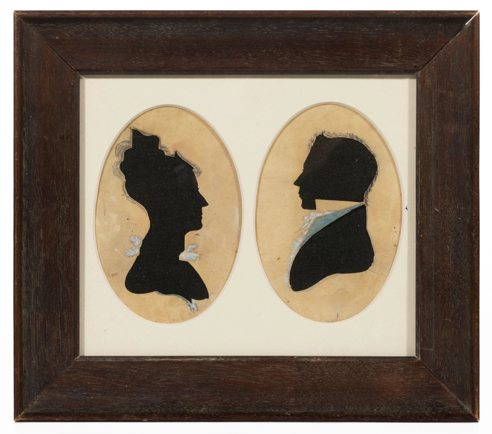 AMERICAN SCHOOL HOLLOW-CUT DOUBLE SILHOUETTE: AMERICAN SCHOOL HOLLOW-CUT DOUBLE SILHOUETTE, with fabric backing, bust-length depictions of a gentleman and a lady, each with watercolor / ink highlights. Housed under glass in an old frame. First ha
