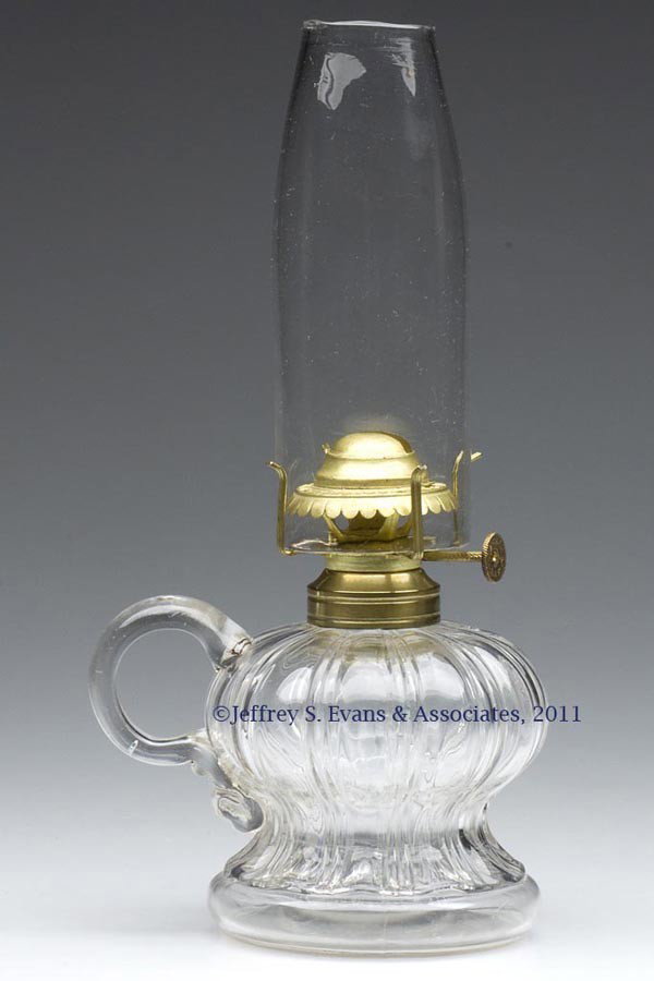 MELON FONT FOOTED FINGER LAMP: MELON FONT FOOTED FINGER LAMP, colorless, waisted form, applied handle, No. 1 Taplin-Brown collar. Fitted with a Holmes, Booth & Haydens No. 0 slip burner, thumbwheel unmarked, deflector embossed "HOL