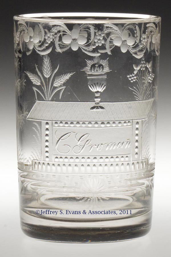 CUT AND ENGRAVED TUMBLER: CUT AND ENGRAVED TUMBLER, colorless non-lead glass, cylindrical form with intricate decorations including a chalice with "IHS" above, sitting on a communion table inscribed "C. Groman", amidst additio