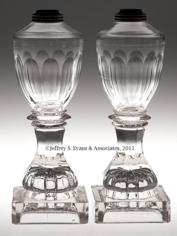 PAIR OF FREE-BLOWN, CUT AND PRESSED WHALE OIL STAN: PAIR OF FREE-BLOWN, CUT AND PRESSED WHALE OIL STAND LAMPS, colorless, each urn-form font cut with 11 lower flutes, raised on a hexagonal baluster-form standard and square base with a rosette underneat