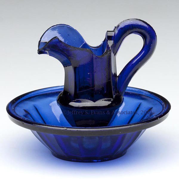 PRESSED PANELED TOY EWER AND BASIN: PRESSED PANELED TOY EWER AND BASIN, cobalt blue, ewer of waisted form with semi-high handle lacking thorns, basin of a slightly lighter shade. Boston & Sandwich Glass Co. 1845-1870. 2 3/8" HOA, 3 1/8"