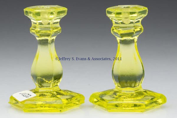 PAIR OF PRESSED HEXAGONAL TOY CANDLESTICKS: PAIR OF PRESSED HEXAGONAL TOY CANDLESTICKS, bright canary yellow, each with rough pontil mark. New England. 1850-1880. 2 1/8" H, 1 1/2" DOA base. Literature: Elsholz, lot 1556, this being the actual p