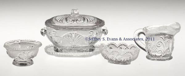 FOUR PRESSED LACY TOYS: FOUR PRESSED LACY TOYS, colorless, comprising a small covered tureen with tray, cream jug with plain foot, circular bowl on low foot, and an oval bowl with plain table ring. Boston & Sandwich Glass Co