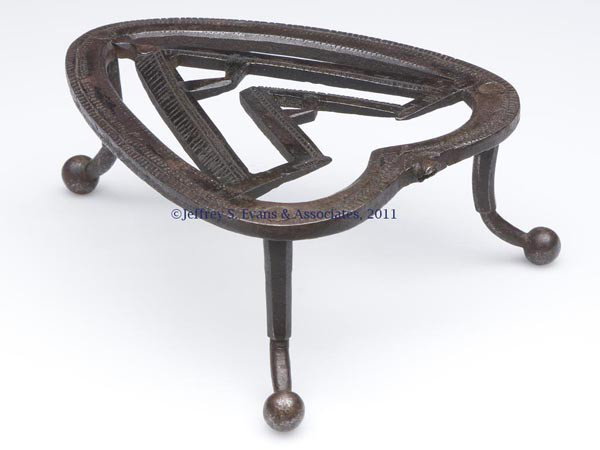 WASHINGTON FAMILY WROUGHT-IRON TRIVET: WASHINGTON FAMILY WROUGHT-IRON TRIVET, heart-form with an applied central "W" or "A" initial, raised on three applied legs terminating in ball feet. Probably originally fitted with a small handle. Fir
