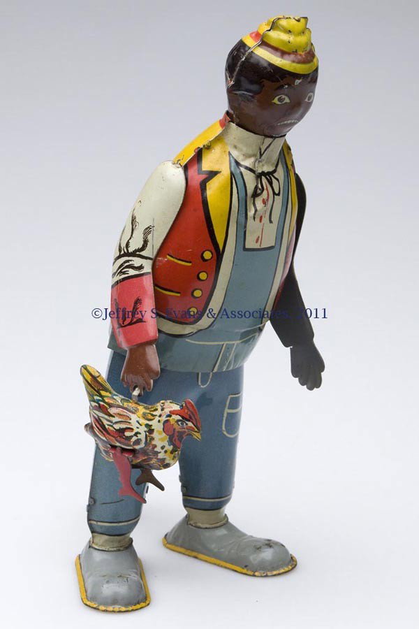 BLACK AMERICANA MARX "HEY-HEY THE CHICKEN SNATCHER: BLACK AMERICANA MARX "HEY-HEY THE CHICKEN SNATCHER" WIND-UP TIN TOY walker figure with articulated arms and torso, attached chicken and dog, lettering under feet. Second quarter 20th century. 8 1/8" H