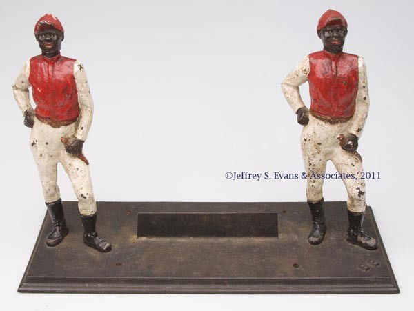 BLACK AMERICANA CAST-IRON BOOT SCRAPPER: BLACK AMERICANA CAST-IRON BOOT SCRAPPER depicting two jockeys bolted to a base, molded "BB" at top corner and "B. B. BUTT / BALTO. MD." underneath, original paint. First half 20th century. 10 1/2" H,