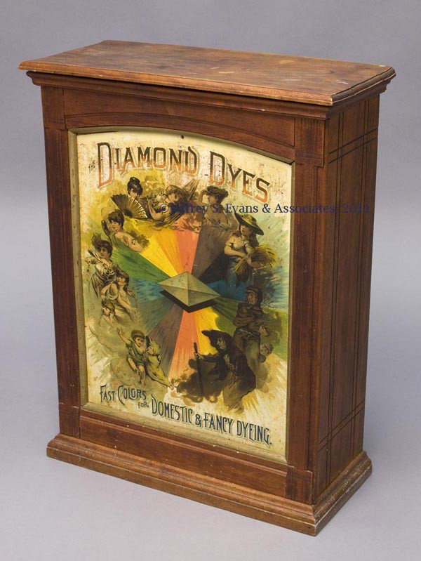 DIAMOND DYES WOOD AND TIN DYE CABINET: DIAMOND DYES WOOD AND TIN DYE CABINET birch cabinet set with a lithographed tin front panel lettered "The Diamond Dyes / Fast Colors for Domestic & Fancy Dyeing.", back with two sliding doors conceali