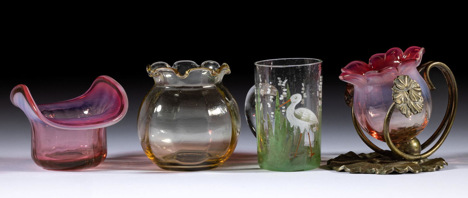 ASSORTED VICTORIAN GLASS TOOTHPICK HOLDERS, LOT OF FOUR,: ASSORTED VICTORIAN GLASS TOOTHPICK HOLDERS, LOT OF FOUR,various colors,comprising a cranberry opalescent floriform example fitted in a metal stand, a cranberry opalescent hat-form fitted into a wheelb