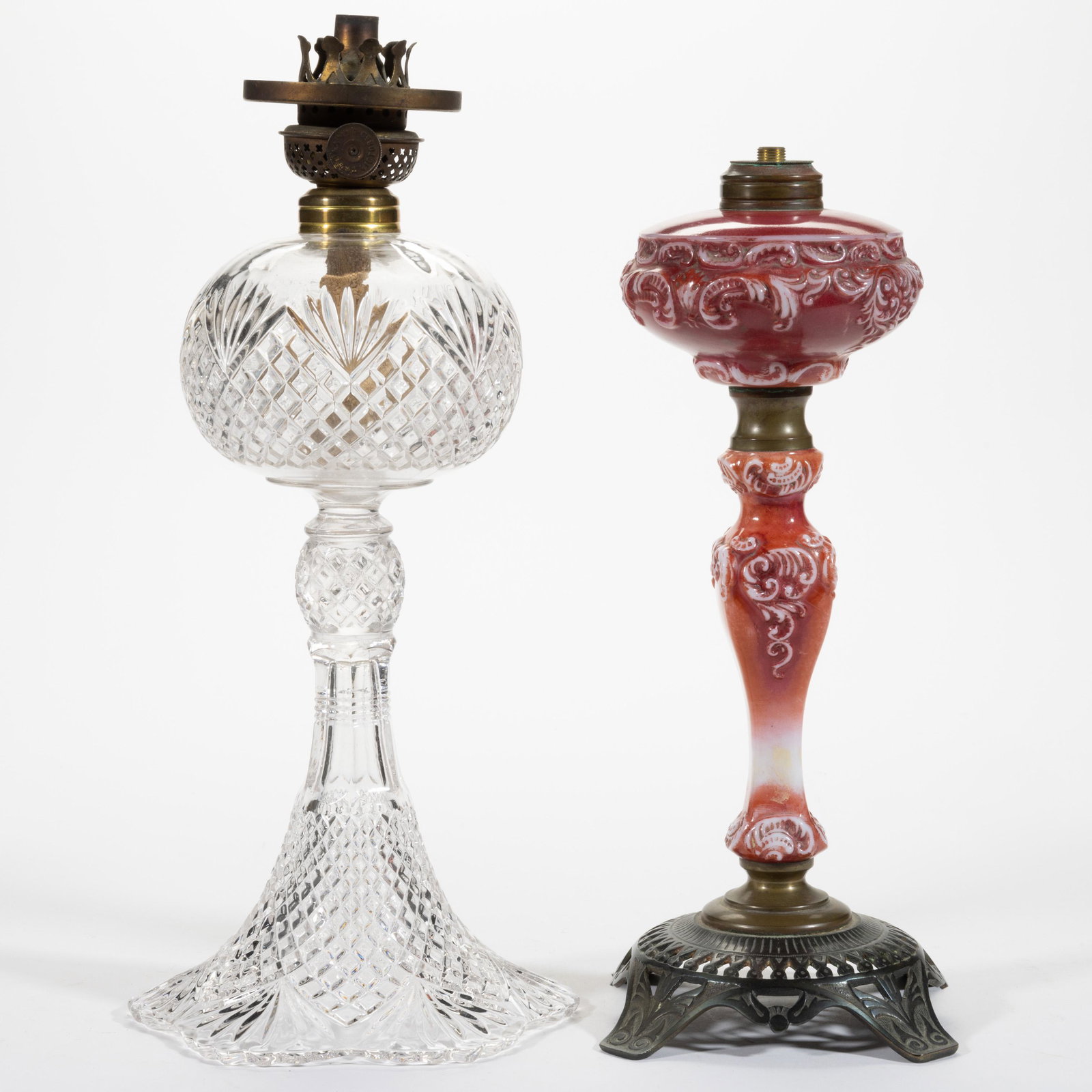 ASSORTED PATTERN KEROSENE BANQUET LAMPS, LOT OF TWO: ASSORTED PATTERN KEROSENE BANQUET LAMPS, LOT OF TWO,comprising a colorless Pineapple and Fan/Shepherd's Plaid example and an opaque white with dark rose decoration Consolidated Ionic Princess, impress