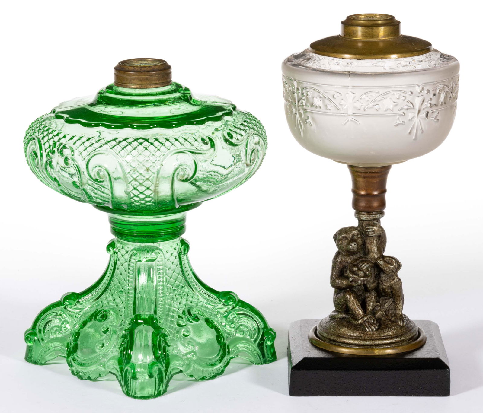 ASSORTED GLASS KEROSENE STAND LAMPS, LOT OF TWO,: ASSORTED GLASS KEROSENE STAND LAMPS, LOT OF TWO,comprising a large green Princess Feather, and a metal figural-stem example featuring two monkeys and a blown-molded font.Various makers.Fourth quarter