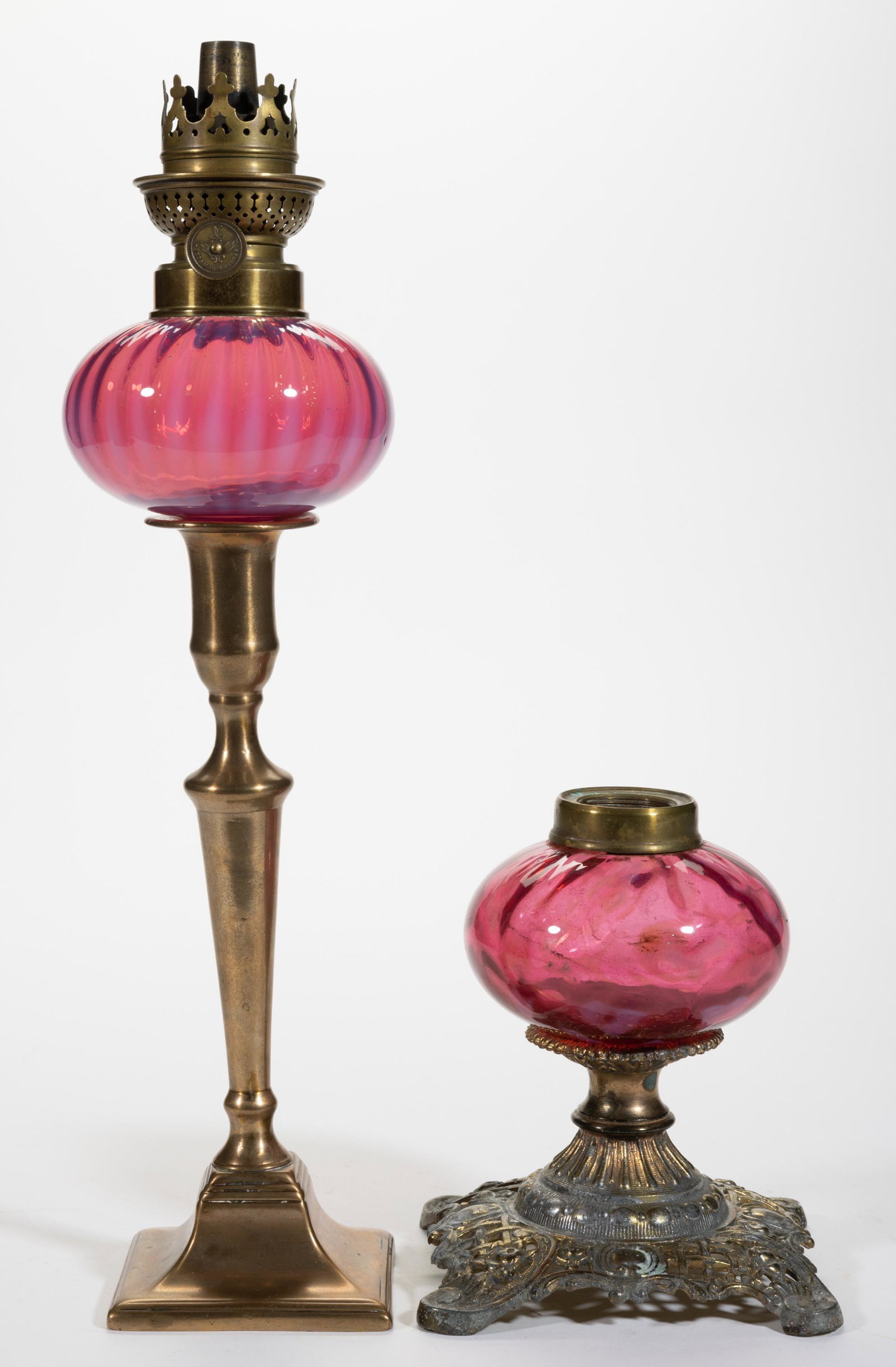 ASSORTED OPALESECNT GLASS KEROSENE LAMPS, LOT OF TWO,: ASSORTED OPALESECNT GLASS KEROSENE LAMPS, LOT OF TWO,cranbery opalescent,comprising a Stripe peg lamp fitted into a brass candlestick and a Floral example fitted into a cast-metal base with brass fini