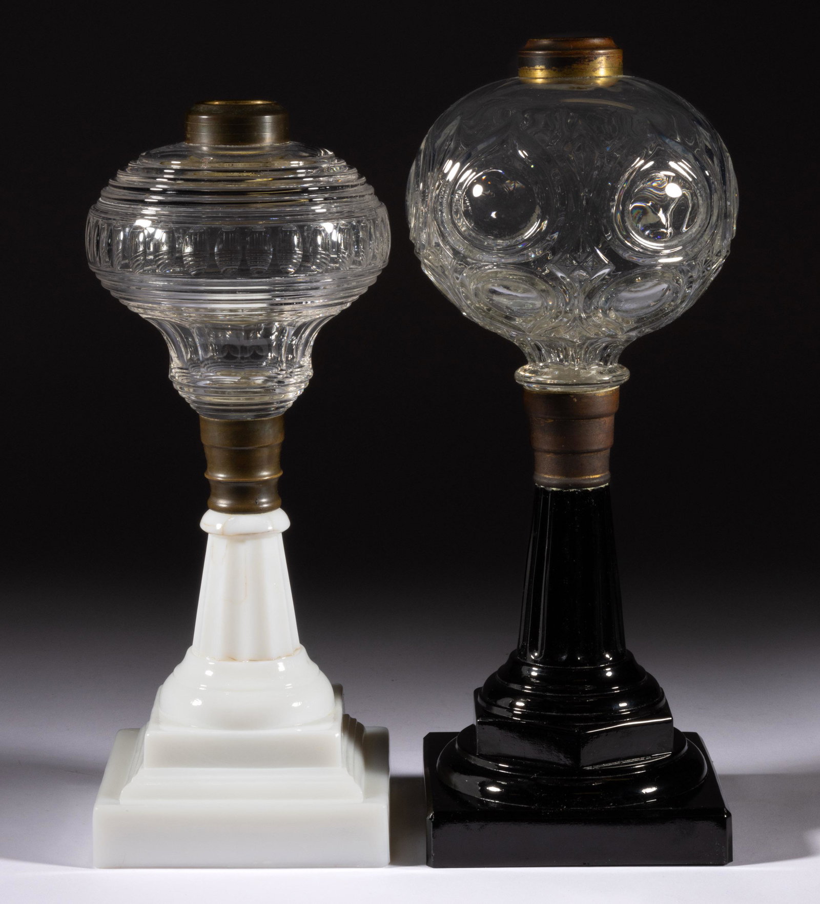 ASSORTED FLINT EAPG KEROSENE STAND LAMPS, LOT OF TWO,: ASSORTED FLINT EAPG KEROSENE STAND LAMPS, LOT OF TWO,colorless fonts,comprising a Flame Bull's Eye raised on an opaque black square base, and a cut oval band example raised on an opaque white square b