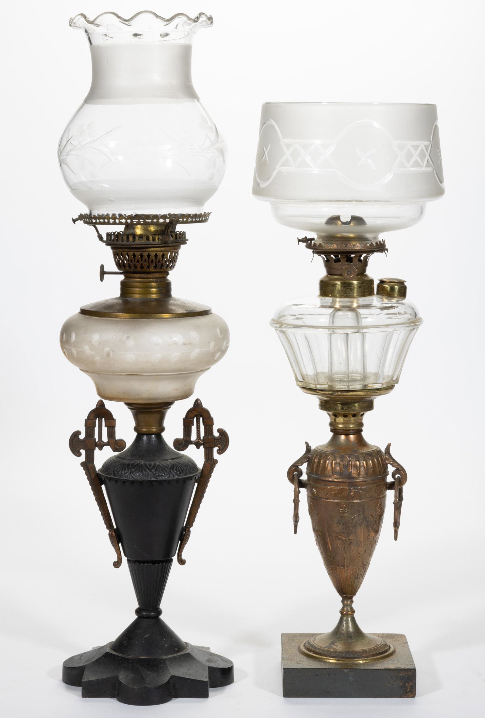 ASSORTED FIGURAL STEM KEROSENE BANQUET LAMPS, LOT OF TWO,: ASSORTED FIGURAL STEM KEROSENE BANQUET LAMPS, LOT OF TWO,colorless fonts,each featuring urn-form standards and metal bases, one fitted with a panelled font, another fitted with a frosted and engraved 