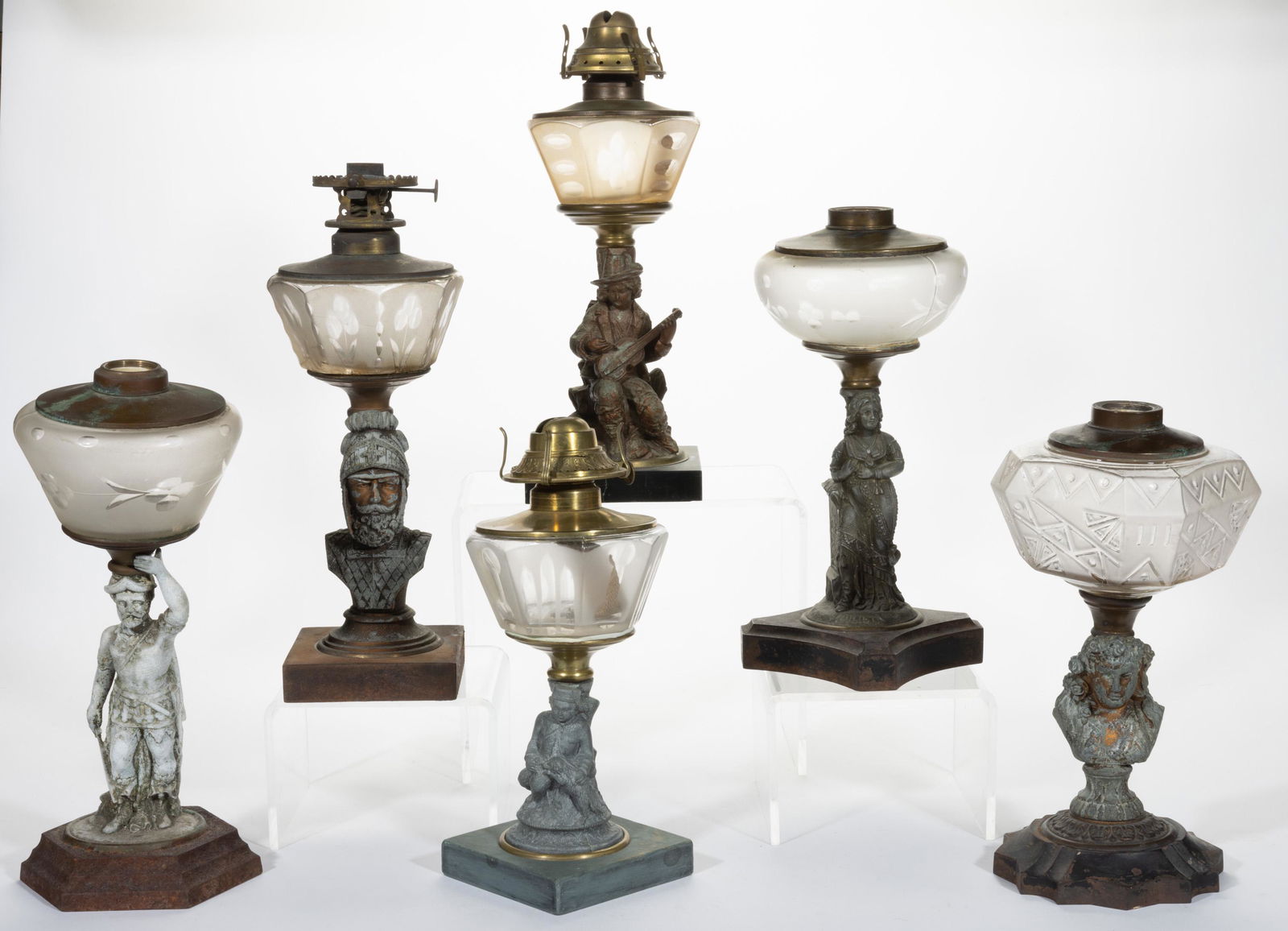 ASSORTED FIGURAL STEM KEROSENE STAND LAMPS, LOT OF SIX,: ASSORTED FIGURAL STEM KEROSENE STAND LAMPS, LOT OF SIX,frosted colorless fonts,including a Knight, a Boy with Dog, and a Man with a Guitar, each having a brass collar with a shoulder plate. Three fitt