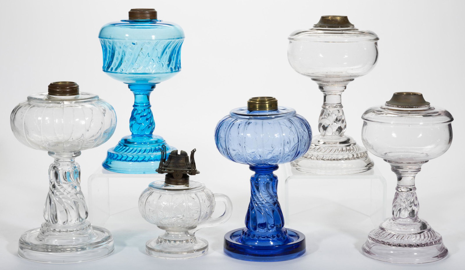 RIVERSIDE GLASS KEROSENE LAMPS, LOT OF SIX,: RIVERSIDE GLASS KEROSENE LAMPS, LOT OF SIX,colorless and blue,including a Beaded Bands, two No. 401, each having a brass collar.Riverside Glass Co.Fourth quarter 19th/early 20th century.4 1/2" to 9 3/