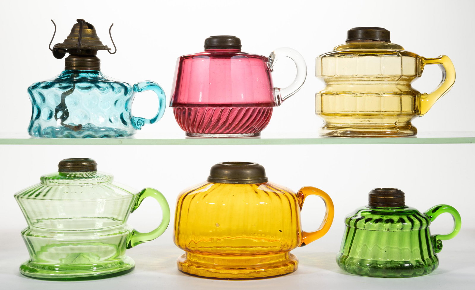 ASSORTED PATTERN KEROSENE FINGER LAMPS, LOT OF SIX: ASSORTED PATTERN KEROSENE FINGER LAMPS, LOT OF SIX,amber, blue, cranberry, and green,each with an applied handle, comprising four various optic patterns, including three rib/panel examples and a thumb