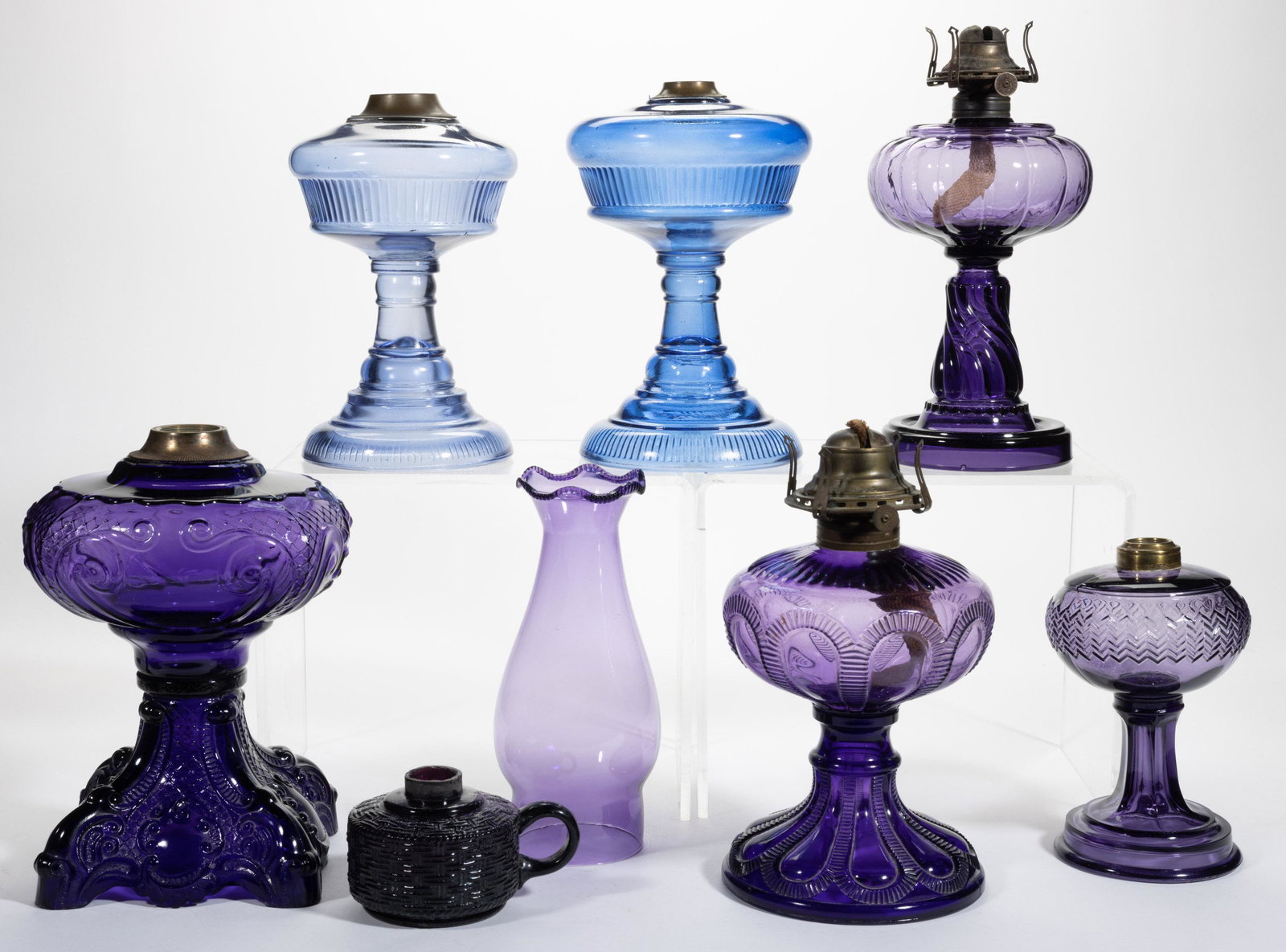 ASSORTED IRRADIATED / STAINED GLASS KEROSENE LAMPS, LOT OF SEVEN: ASSORTED IRRADIATED / STAINED GLASS KEROSENE LAMPS, LOT OF SEVEN, deep purple or medium blue,including a massive Princess Feather, a Basketweave finger lamp, and two Riverside Rib examples with later 