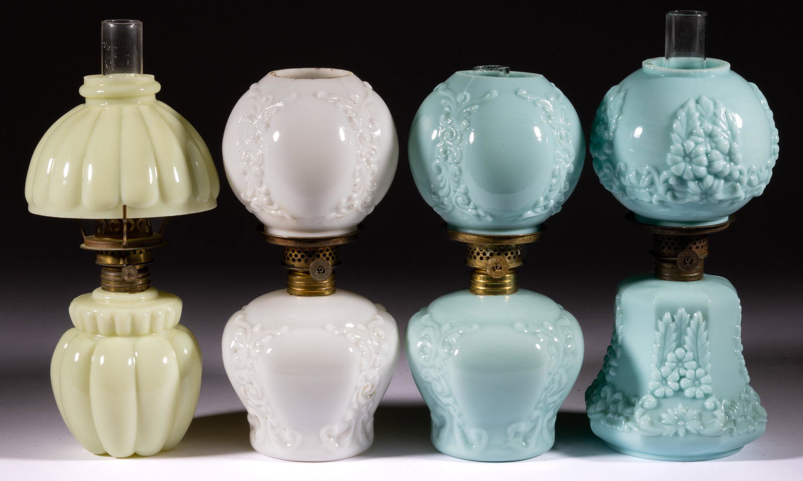 ASSORTED PATTERN OPAQUE GLASS MINIATURE LAMPS, LOT OF FOUR: ASSORTED PATTERN OPAQUE GLASS MINIATURE LAMPS, LOT OF FOUR,opaque blue, opaque white, and custard, each fitted with a matching patterned shade,comprising two Embossed Scrolls/Smith I, fig. 234 example