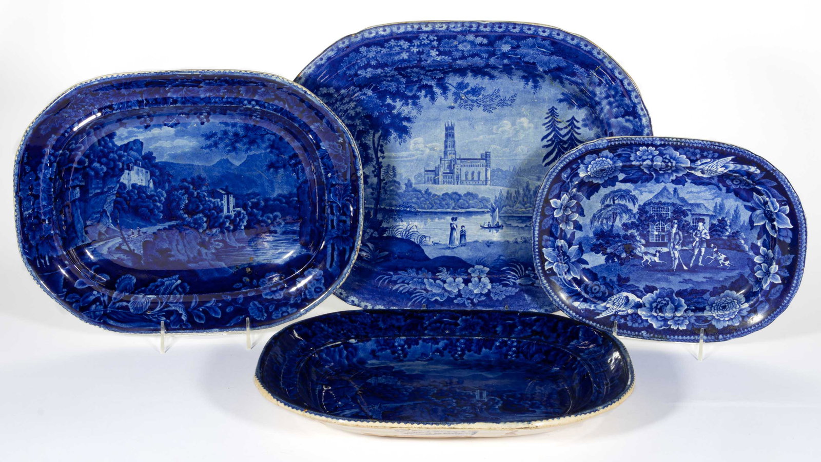 STAFFORDSHIRE PEARLWARE TRANSFER-PRINTED CERAMIC PLATTERS, LOT OF FOUR: STAFFORDSHIRE PEARLWARE TRANSFER-PRINTED CERAMIC PLATTERS, LOT OF FOUR,each having dark blue transfer scenes, comprising one example from the Hunting Series depicting two gentlemen with guns and hunti