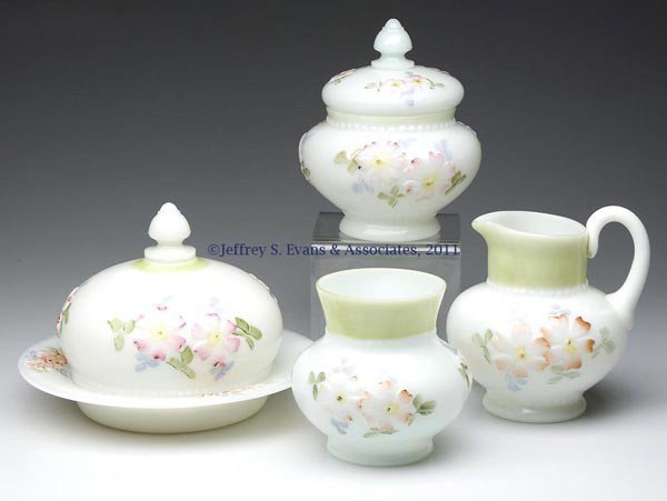 COREOPSIS ASSEMBLED FOUR-PIECE TABLE SET: COREOPSIS ASSEMBLED FOUR-PIECE TABLE SET, opaque white/milk glass with polychrome decoration, pale green bands, comprising a butter dish, covered sugar bowl, creamer with applied handle with pressed f