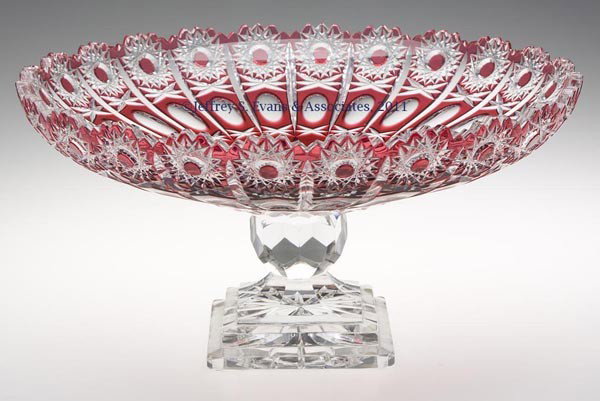 CUT OVERLAY LEAD CRYSTAL LARGE COMPOTE: CUT OVERLAY LEAD CRYSTAL LARGE COMPOTE, red to colorless, shallow bowl with hobstar and oval cuttings, raised on a three-step square star-cut foot. Second half 20th century. 7 1/2" H, 14" D. Provenanc