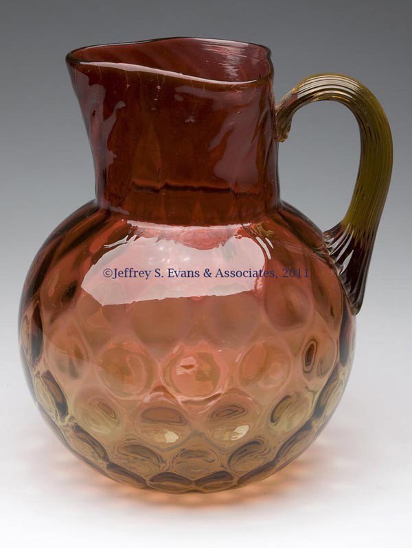 AMBERINA PHOENIX SPOT-OPTIC WATER PITCHER: AMBERINA PHOENIX SPOT-OPTIC WATER PITCHER, ball shape with tricorner rim, applied reeded handle, polished pontil mark. Phoenix Glass Co. Fourth quarter 19th century. 8 1/2" H. Literature: Marple - Pho