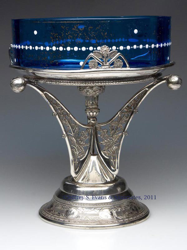 VICTORIAN DECORATED BRIDE'S BASKET: VICTORIAN DECORATED BRIDE'S BASKET, sapphire blue with white enamel and gilt decoration, fitted in a tripartite Pairpoint Mfg. Co. weighted quadruple-plate stand. Late 19th/early 20th century. 11" H, 