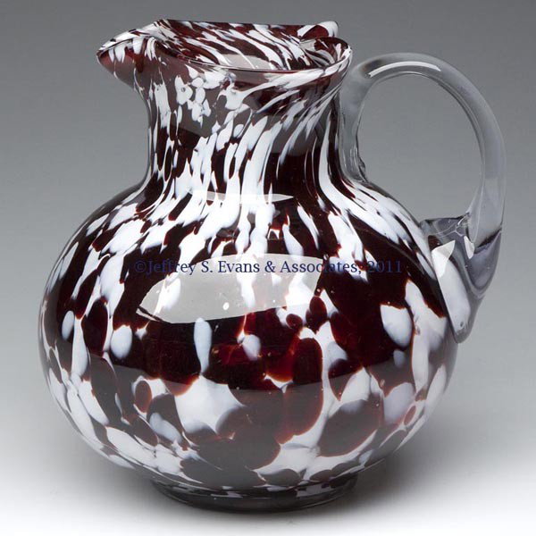 VICTORIAN MOTTLED GLASS WATER PITCHER: VICTORIAN MOTTLED GLASS WATER PITCHER, maroon and opaque white, tooled heart-shaped rim, colorless applied handle, polished pontil mark. Late 19th/early 20th century. 7 1/4" HOA. Provenance: From a pr