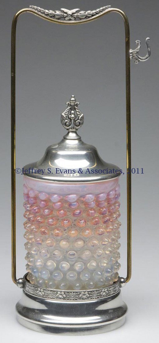 OPALESCENT HOBNAIL PICKLE CASTER: OPALESCENT HOBNAIL PICKLE CASTER, pale rubina opalescent, polished pontil mark and base, fitted in a Simpson, Hall & Miller frame, marked "0856", with cover, lacking tongs. Rim of jar polished during 