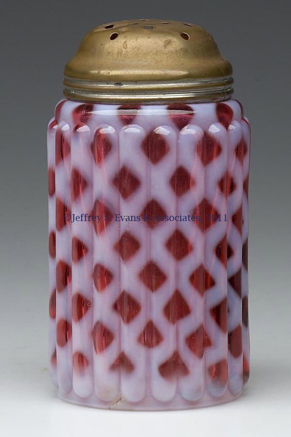 RIBBED OPAL LATTICE SUGAR SHAKER: RIBBED OPAL LATTICE SUGAR SHAKER, cranberry with strong opalescence, period lid. Late 19th/early 20th century. 4 1/2" HOA. Provenance: Personal collection of Judith (Judy) Cronin, Orleans, MA.