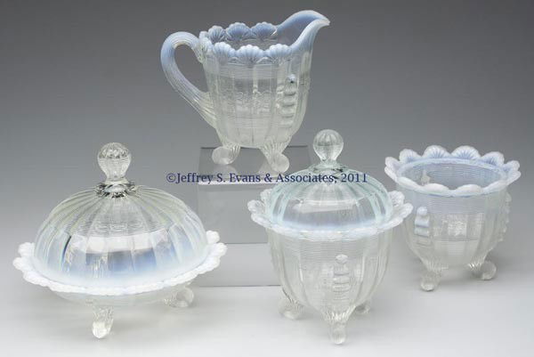 KLONDYKE / FLUTED SCROLL THREE-PIECE TABLE SET: KLONDYKE / FLUTED SCROLL THREE-PIECE TABLE SET, colorless opalescent, comprising a butter dish, covered sugar and spooner, each raised on three feet. Together with a Jackson creamer, raised on three f