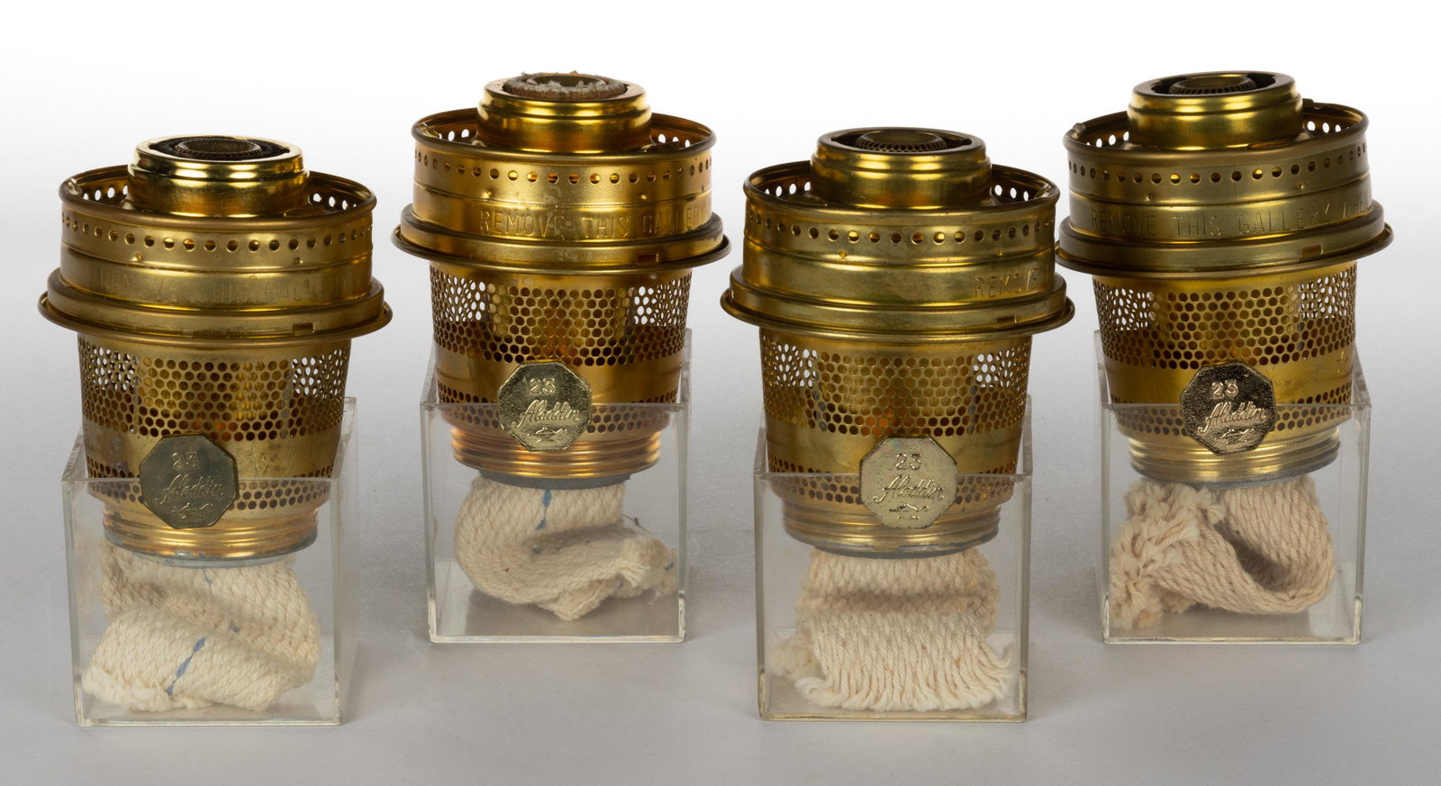 ALADDIN MODEL 23 BRASS KEROSENE LAMP BURNERS, LOT OF FOUR: ALADDIN MODEL 23 BRASS KEROSENE LAMP BURNERS, LOT OF FOUR, each complete with a period flame spreader, one lacking a flame spreader. The Mantle Lamp Company of America (Aladdin). 20th century.