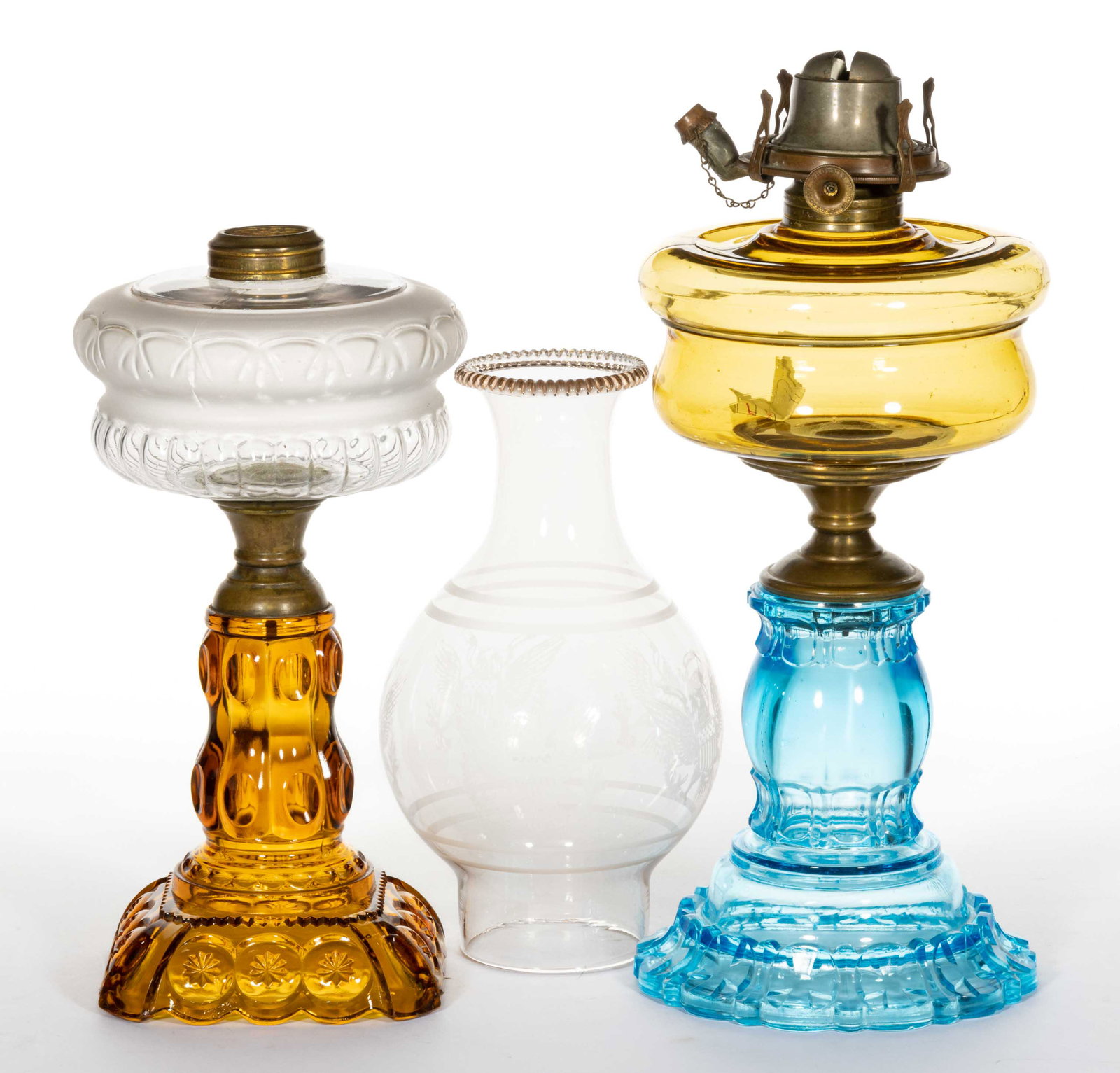 ASSORTED ADAMS & CO. PATTERN KEROSENE STAND LAMPS, LOT OF TWO: ASSORTED ADAMS & CO. PATTERN KEROSENE STAND LAMPS, LOT OF TWO, comprising a Moon and Star, colorless with frosting font and honey amber base; and an Apollo example with a light amber font and blue